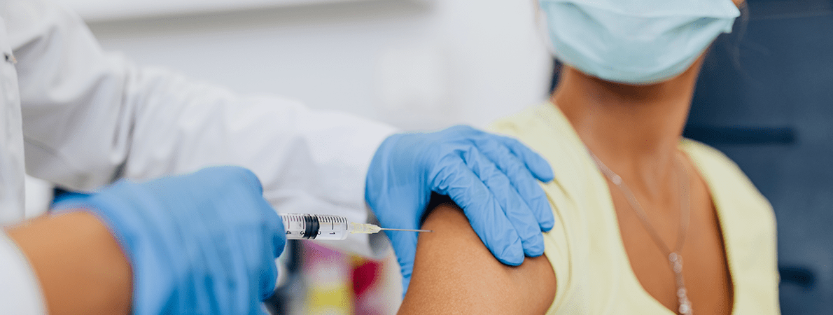 Female doctor or nurse giving shot or vaccine to a patient's shoulder