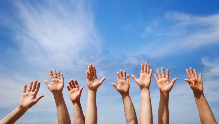 Four pairs of hands raised towards a blue sky.
