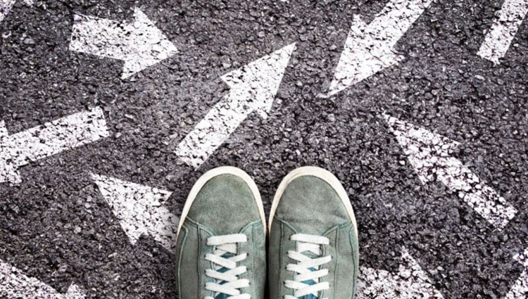 Pair of green trainers standing on white arrows on the road