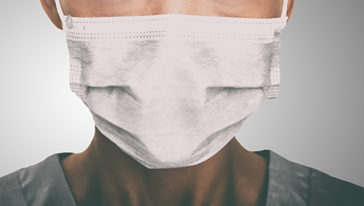 Close up of person wearing a surgical mask.