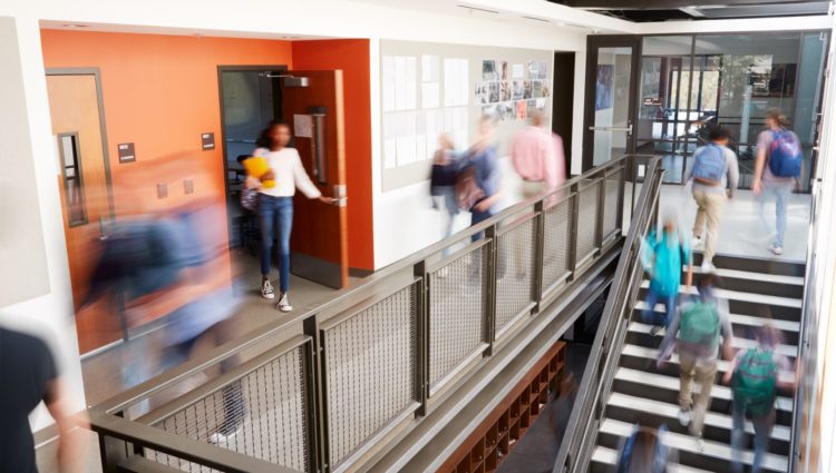 Busy college corridor with students going up stairs