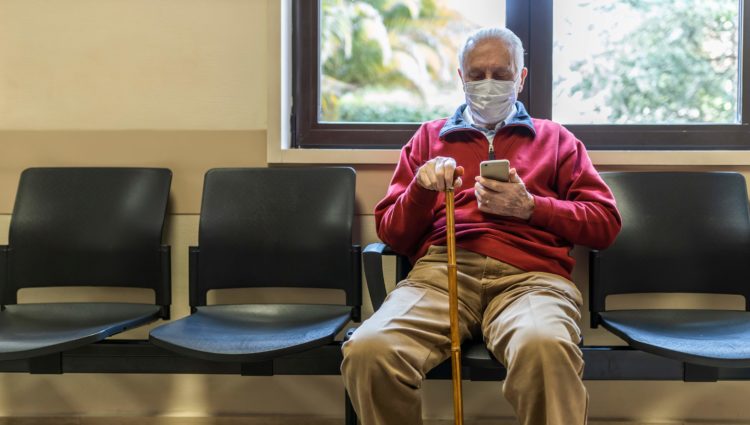 A man sat in a hospital corridor looking at his phone
