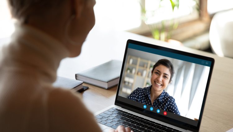 Woman on a laptop using a video calling platform talking to a colleague