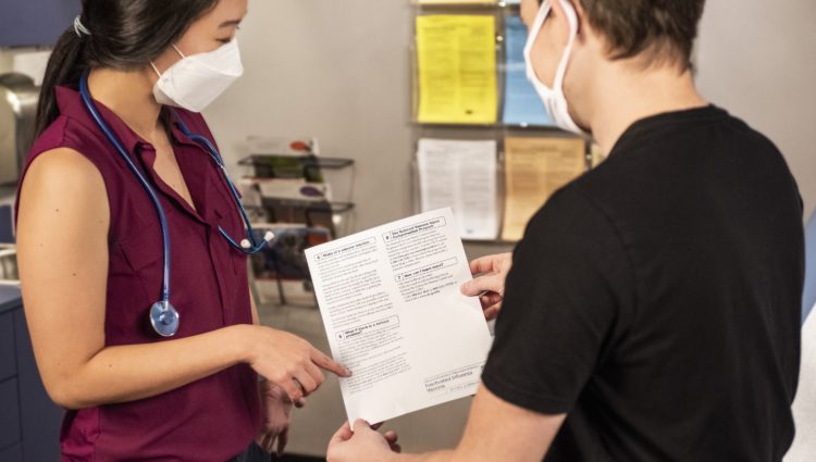 A doctor and patient converse over a medical document