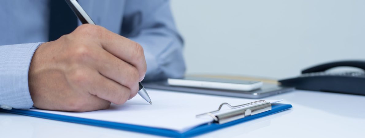 close-up picture of a man taking notes with pen and paper