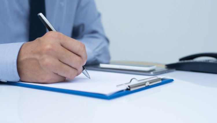 close-up picture of a man taking notes with pen and paper