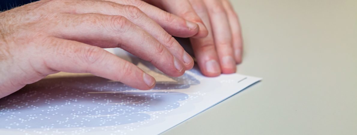 close up picture of a person reading a document in braille