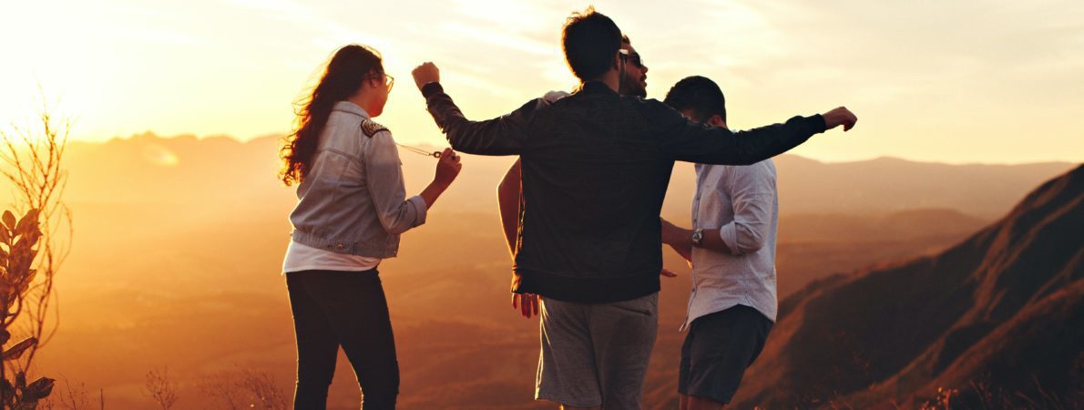 A group of four young people enjoying the sunset view on a hill