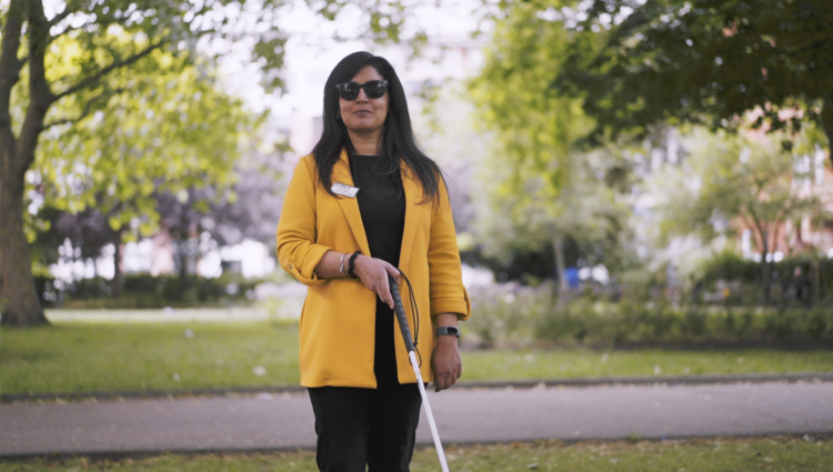 A picture of Renu walking around a park holding her cane