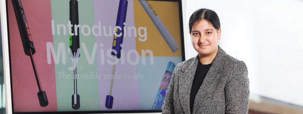 Picture of Ramneek smiling in front of a screen that says 'Introducing My Vision'